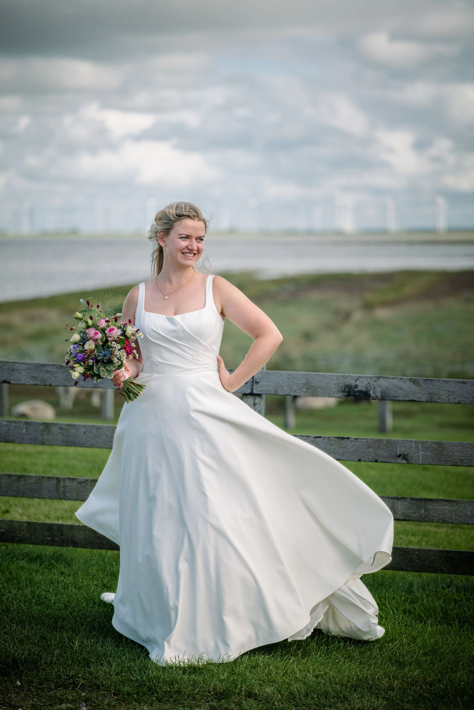 Schöne Braut im weißen Brautkleid auf dem Deich in Nordfriesland